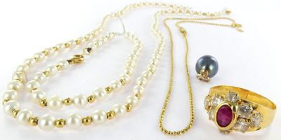 a close up of a necklace, bracelet, and ring on a white surface