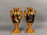 une paire de vases en or ornés de peintures, posés sur une table