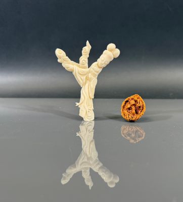 une petite figurine blanche posée à côté d'une noix à moitié mangée