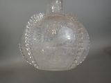 a clear glass bottle with a handle hanging from it ' s side