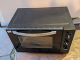 a small black oven sitting on the floor next to a wall