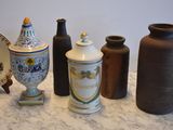 many different vases on a table with a plate in the background