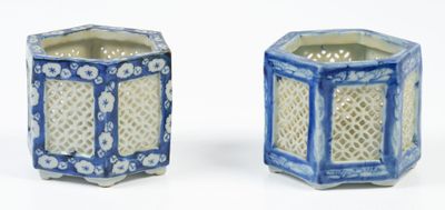 une paire de vases hexagonaux bleus et blancs posés sur une surface blanche