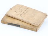 two old books sitting on top of each other on a white surface