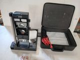 une valise noire contenant une cafetière, posée sur une table