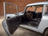 a silver car with its door open in front of a brick wall