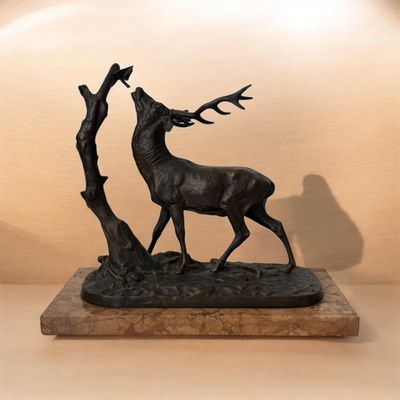 statue d'un cerf aux bois accrochés à un arbre, posée sur un socle en marbre