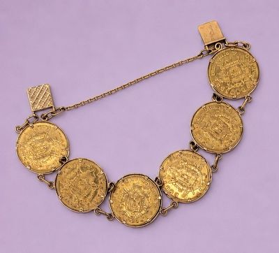 un gros plan d'un bracelet composé de pièces d'or sur fond violet