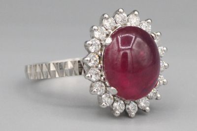 gros plan d'une bague avec une pierre rouge entourée de diamants blancs