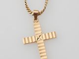 a gold cross pendant with a chain on a white background