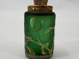 a small green glass bottle with a gold decoration on it