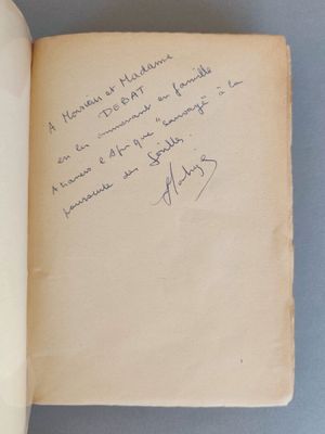 un livre ouvert, sur lequel est posée une note manuscrite, posé sur une table