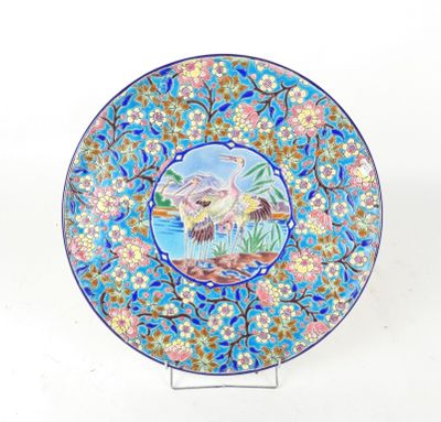 une assiette bleue sur laquelle est représenté un oiseau et des fleurs