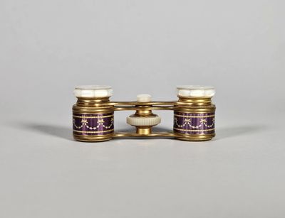 une paire de jumelles en verre doré et violet posées sur une surface blanche