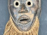 an old wooden mask with long hair on a black background