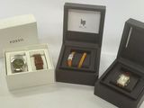 three boxes with watches and a watch in them on a white surface