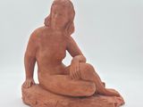 statue d'une femme assise sur un rocher, sur fond blanc