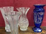 trois vases en verre posés sur une table près d'un mur rouge