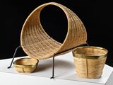 a wicker chair and two baskets on a white pedestal