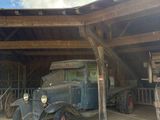 une vieille voiture garée dans un garage, sous une structure en bois