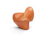 une sculpture orange représentant un objet en forme de cœur posé sur une surface blanche