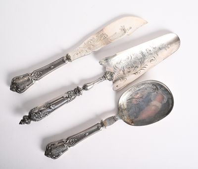trois cuillères en argent et un repose-cuillère posés sur une surface blanche