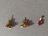 three pairs of gold and ruby earrings on a gray surface