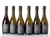 six bottles of wine are lined up in a row on a white surface