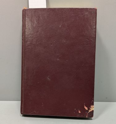 un vieux livre posé sur une table, à côté d'un cadre photo