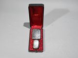 a small red box with two silver stones in it