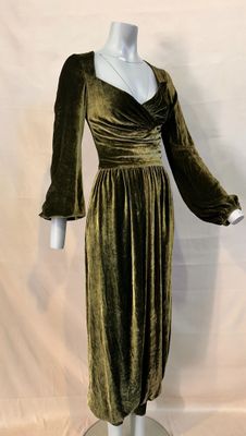 a woman ' s green velvet dress on a mannequin base