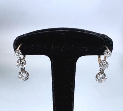 a close up of a pair of earrings on a black stand