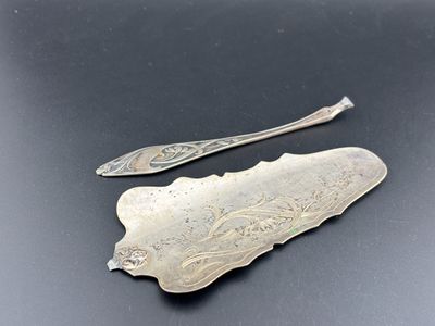 deux cuillères en argent et un repose-cuillère posés sur une surface noire