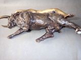 a bronze statue of a bull laying down on the ground