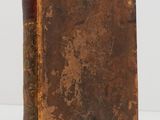 an old book sitting on top of a table next to a white wall
