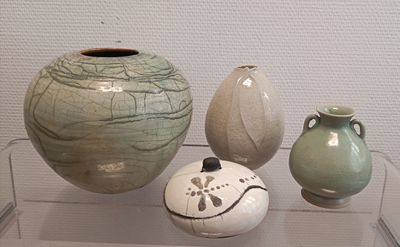 three vases on display in a glass case