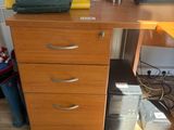 a wooden desk with drawers and a bag on top of it