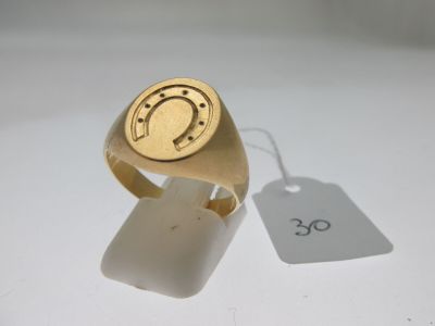 une bague en or ornée d'un fer à cheval, à côté d'une étiquette de prix