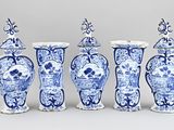 quatre vases bleus et blancs sont alignés sur un fond gris