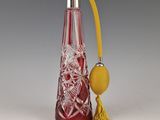 une bouteille en verre rouge avec un pompon jaune à côté