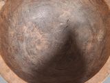 an old wooden bowl sitting on top of a table next to a wall