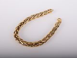 un bracelet en or avec un motif de tresse sur fond blanc