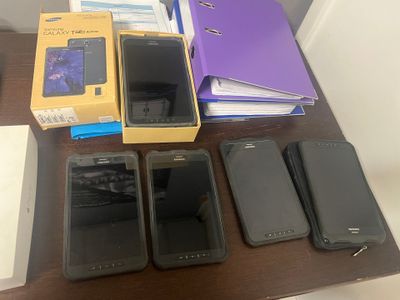 several cell phones are lined up on a table next to a notebook