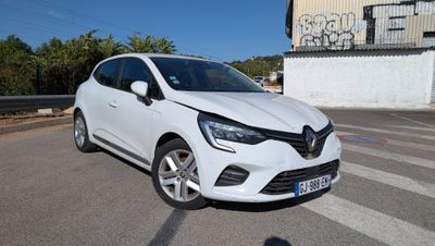 une voiture blanche garée dans un parking à côté d'un bâtiment