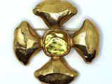 yellow stone cross broochle on white surface with white background