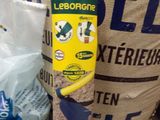 a bag of seed next to a shovel and a bag of seed