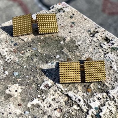 une paire de boucles d'oreilles en or posée sur une dalle de béton