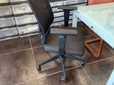 une chaise de bureau noire placée devant une table en verre