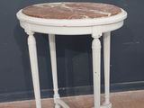 une vieille table blanche avec un plateau en marbre, posée sur un sol recouvert de moquette