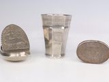 une coupe en argent et une cuillère en argent à côté d'une pièce de monnaie